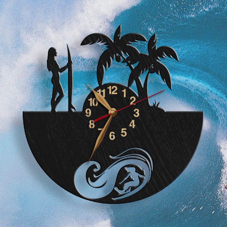 Pu&ograve; includere: Orologio da parete nero a tema surf. L'orologio presenta la silhouette di un surfista, palme e una donna che tiene una tavola da surf. Le lancette dell'orologio sono dorate e lo sfondo &egrave; un'onda blu.