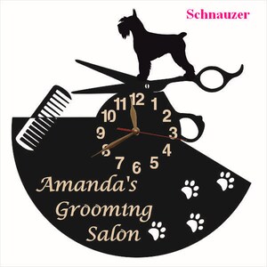 May include: Black and white clock with a silhouette of a Schnauzer dog, scissors, and a comb. The clock face has Roman numerals and the text "Amanda's Grooming Salon" is below the clock face.