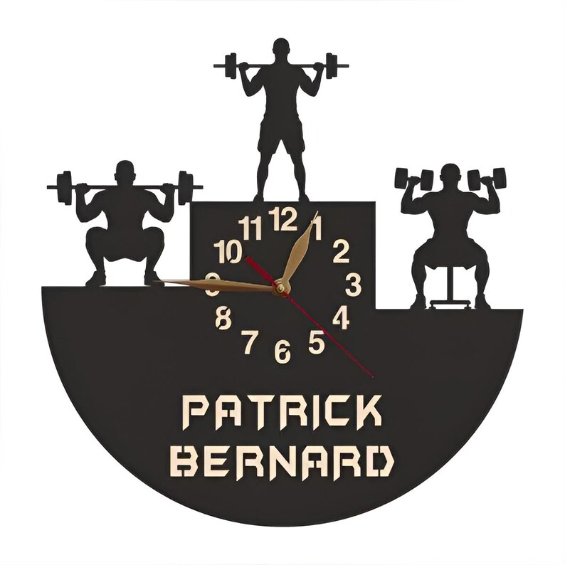 May include: Black and white silhouette of a clock with a weightlifting theme. The clock face has black numbers and a gold hand. The clock is surrounded by three weightlifters. The clock face has the name "PATRICK BERNARD" printed below it.
