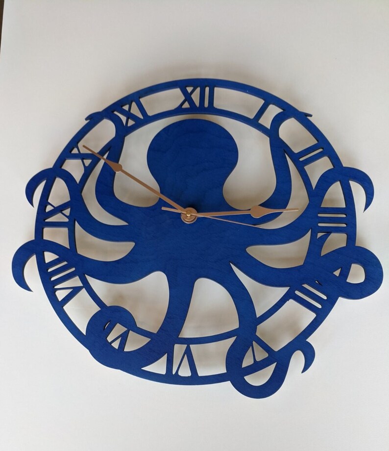 May include: A blue wooden wall clock with an octopus design. The clock face has Roman numerals and copper-coloured hands. The octopus is central within a circular frame, creating a nautical theme for home decor.