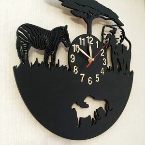 May include: Black clock with a zebra, elephant, and lion cutouts. The clock face has black numbers and gold hands.