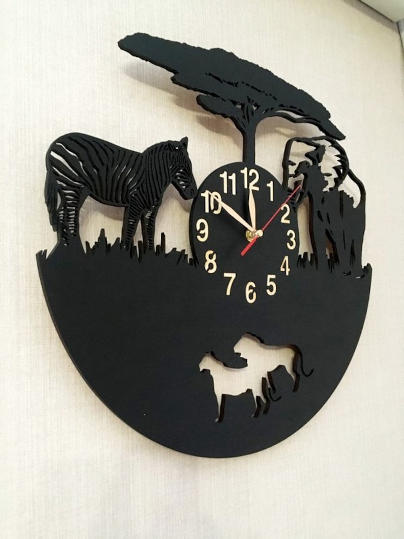 May include: Black clock with a zebra, elephant, and lion cutouts. The clock face has black numbers and gold hands.
