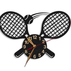 May include: Black tennis racket wall clock with gold numbers and hands. The clock is shaped like two tennis rackets with a tennis ball in the middle.