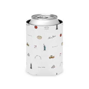 Puede incluir: Un enfriador de latas blanco con un patrón repetido de iconos de la ciudad de Nueva York, que incluyen una manzana, una rosquilla, un taxi, una porción de pizza y la Estatua de la Libertad. Las palabras "New York", "Empire State" e "I NY" también son visibles.