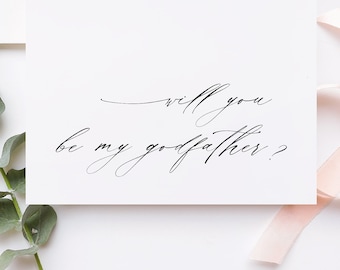 May include: A white card with black calligraphy that reads "Will you be my godfather?"  The card is surrounded by a sprig of eucalyptus, a pink ribbon, a wooden stamp, and a white envelope.