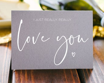 May include: A gray card with the text "I just really, really love you" in white script font with a small white heart below the text.