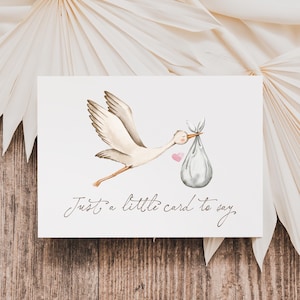 May include: A watercolour greeting card depicting a stork in flight, carrying a bundle. The stork is white with brown details, and the bundle is grey. A small pink heart is beside the stork. The card reads, "Just a little card to say."