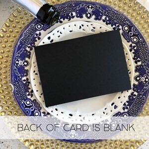 Puede incluir: Una tarjeta negra con borde blanco se encuentra sobre un plato con dise&ntilde;o azul y blanco. El plato est&aacute; sobre un plato de carga dorado. El texto "BACK OF CARD IS BLANK" es visible en la parte inferior de la imagen.