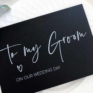 Pode incluir: Cart&atilde;o preto com texto branco que diz "to my groom" com um pequeno s&iacute;mbolo de cora&ccedil;&atilde;o e "on our wedding day" abaixo.