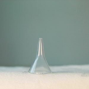 May include: A clear plastic ear syringe, also known as an ear bulb syringe, is on a white surface.