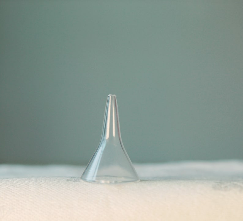 May include: A clear plastic ear syringe, also known as an ear bulb syringe, is on a white surface.