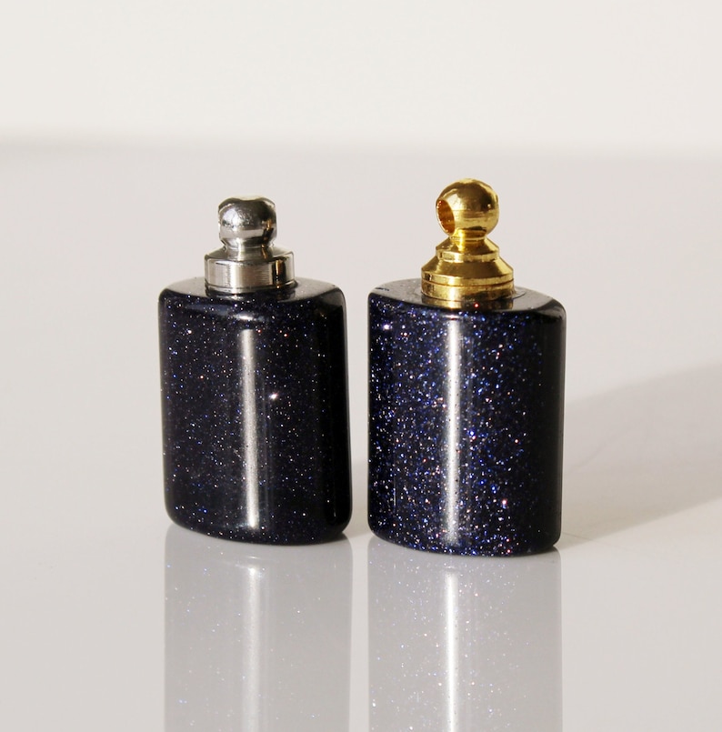 May include: Two small, dark blue glass bottles with silver and gold tops. The bottles have a sparkly, glittery finish.