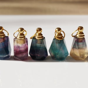 May include: Five small, faceted, gemstone bottles with gold stoppers. The bottles are in shades of green, blue, purple, and yellow.