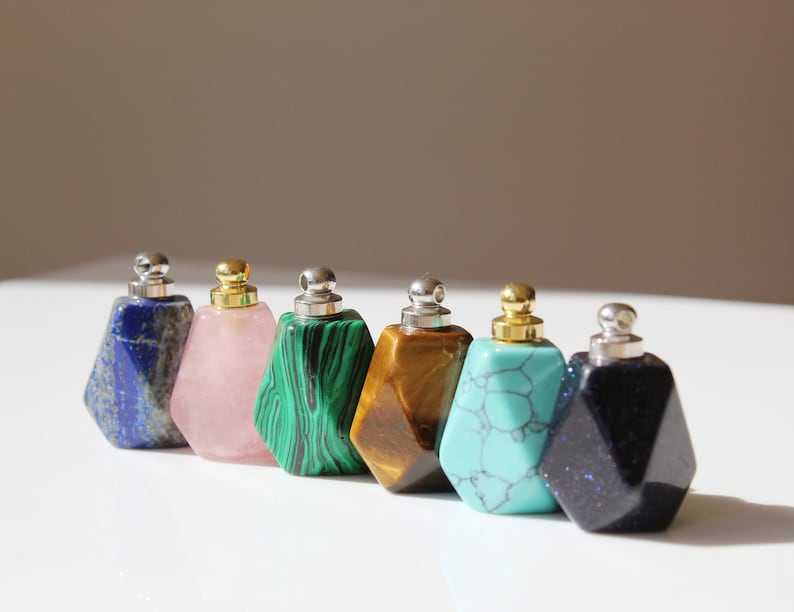 May include: Seven small gemstone bottles with gold and silver caps. The bottles are in the following colors: blue, pink, green, brown, turquoise, and dark blue.