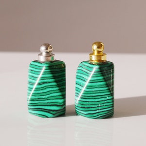 May include: Two green and black malachite stone bottle stoppers with silver and gold metal tops.