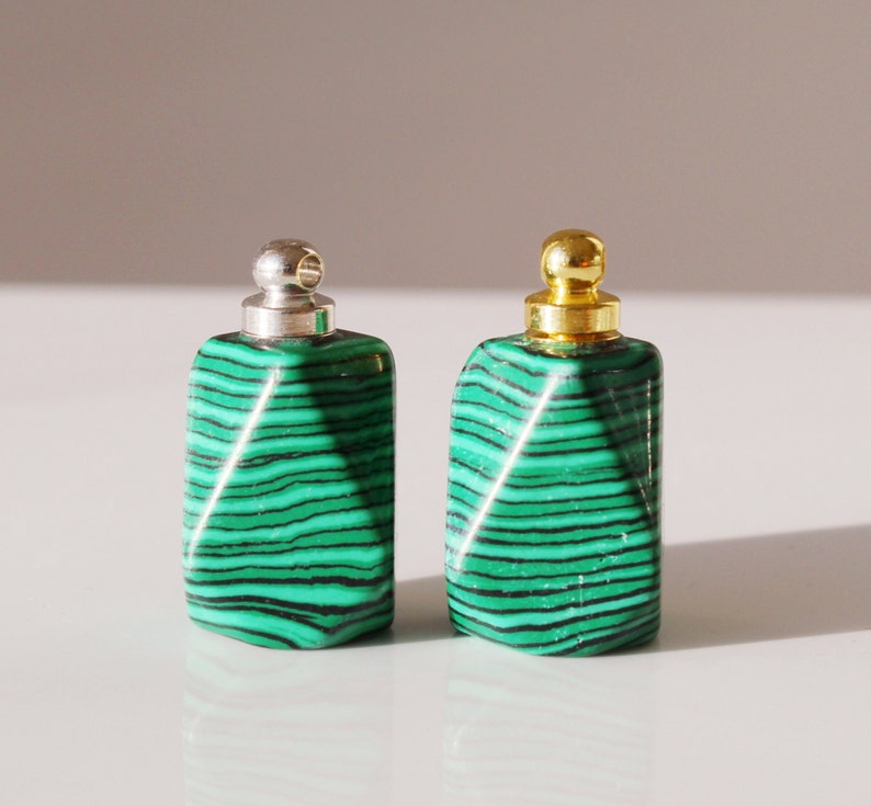 May include: Two green and black malachite stone bottle stoppers with silver and gold metal tops.
