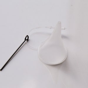 May include: A clear plastic funnel with a thin, flexible spout and a small loop at the top. A thin metal wire with a loop at one end is attached to the funnel.