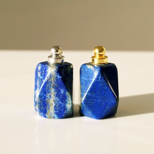 May include: Two small, geometrically shaped bottles made of blue lapis lazuli stone with silver and gold caps.