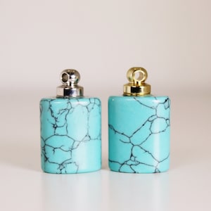 May include: Two turquoise blue pendant charms with silver and gold caps. The charms are rectangular and have a marbled pattern.