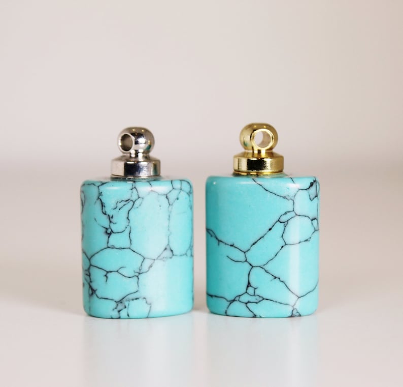 May include: Two turquoise blue pendant charms with silver and gold caps. The charms are rectangular and have a marbled pattern.