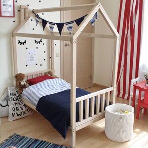 Front view of a natural solid wood Montessori house bed frame with removable side rails for child safety.