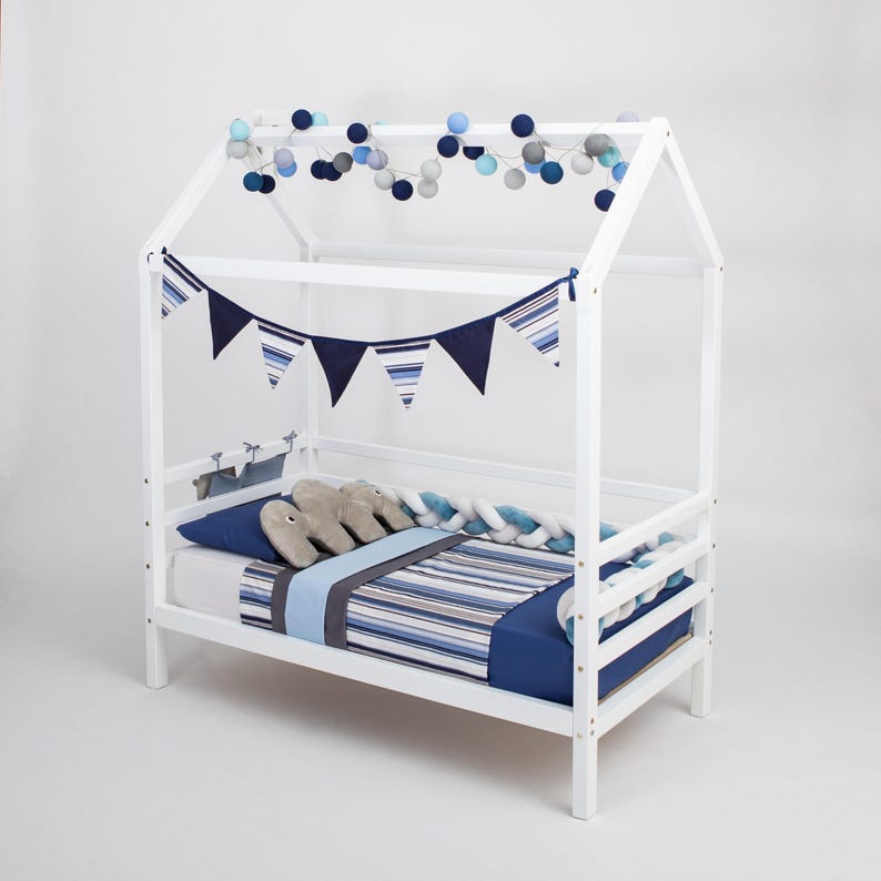 White solid wood toddler house bed frame decorated with navy drapes, making a great 1st birthday gift.