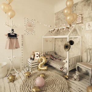 Natural solid wood canopy bed decorated with pastel drapes and balloons for a toddler girl bedroom.