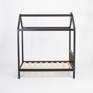 Empty black house bed frame on raised legs showing the wooden mattress slat foundation from a front-quarter angle.