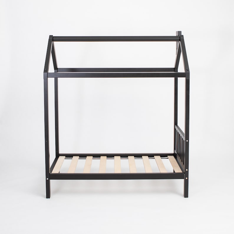 Empty black house bed frame on raised legs showing the wooden mattress slat foundation from a front-quarter angle.