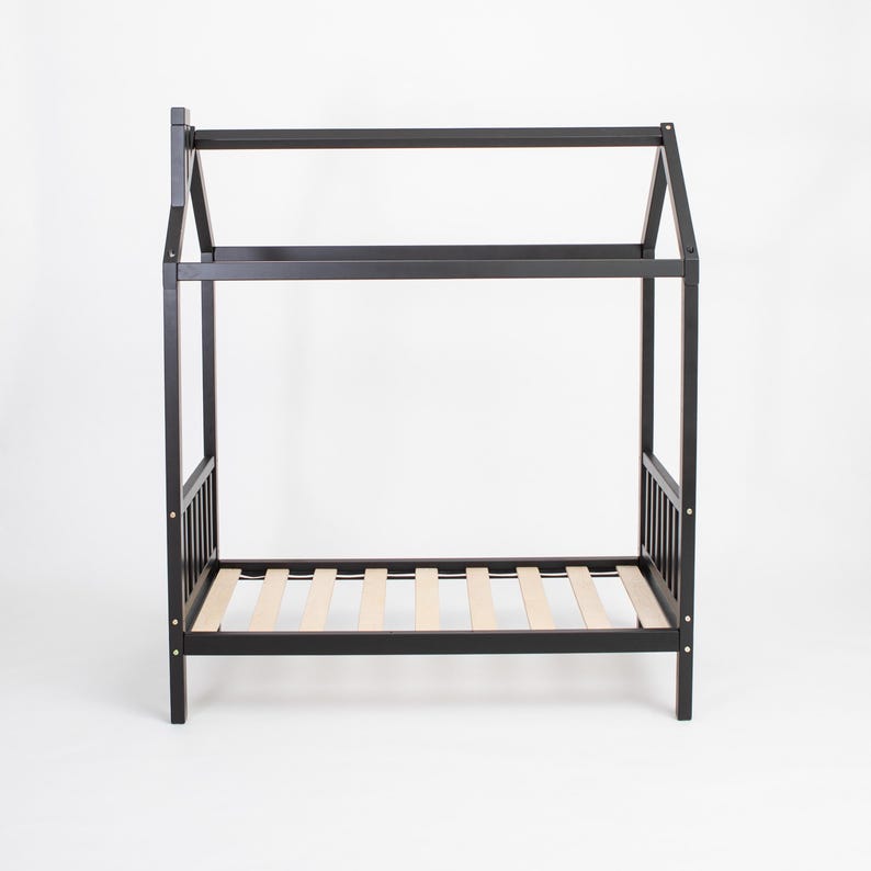 Black solid wood platform house bed frame with birch plywood mattress support slats on a studio backdrop.