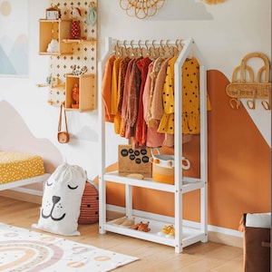 White wooden house-shaped clothing rack with storage shelves in a warm toddler bedroom setting