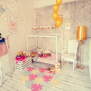 High-angle perspective of the white painted house bed frame in a whimsical girl bedroom setup with decorative letters and balloons.