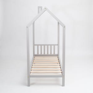 Direct head-on view of the light grey wooden house bed frame on legs showing precise symmetrical roofline and mattress slats.