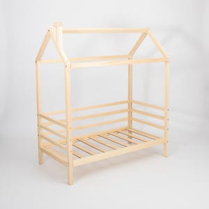 Natural solid wood toddler house bed frame on legs with removable safety rails and birch plywood mattress slats.
