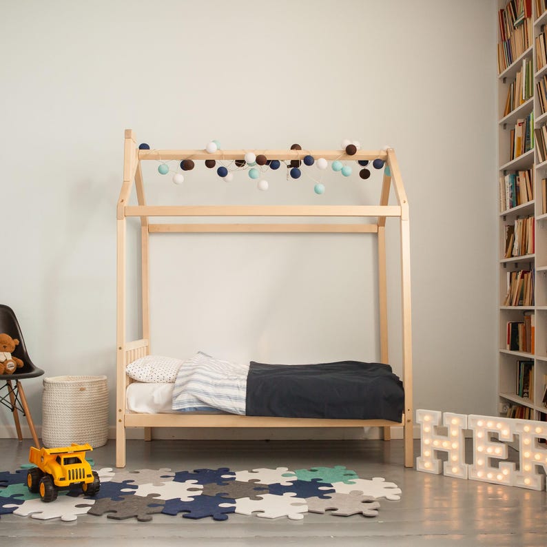 Straight side profile of the raised natural wood house bed displaying frame ground clearance and slatted base construction.