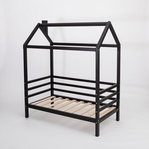 Black solid wood toddler house bed frame with birch plywood slats and removable safety rails on a white background.