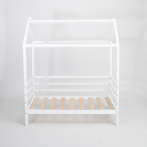 White solid wood Montessori house bed frame on legs with visible birch plywood mattress support slats.