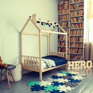 Natural solid wood childrens cabin bed set up near bookshelves to encourage bedtime reading habits.