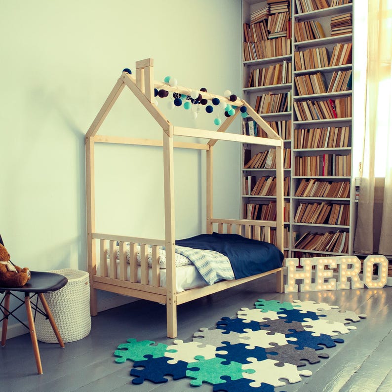 Natural solid wood childrens cabin bed set up near bookshelves to encourage bedtime reading habits.
