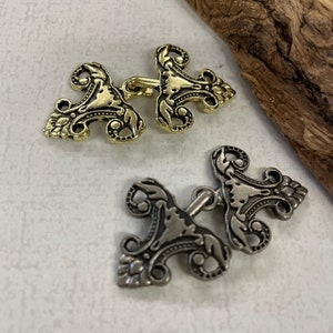 Puede incluir: Dos cierres metálicos ornamentados, uno dorado y otro plateado, con intrincados diseños florales. Estos cierres son perfectos para agregar un toque de elegancia a la ropa o las manualidades.