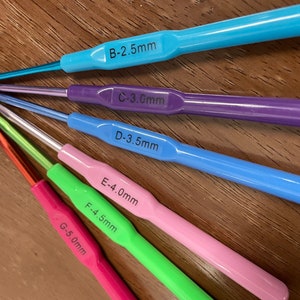 Pu&ograve; includere: Un set di sei ferri da uncinetto di diversi colori e dimensioni. I ferri sono etichettati con la loro dimensione in millimetri: B-2,5 mm, C-3,0 mm, D-3,5 mm, E-4,0 mm, F-4,5 mm e G-5,0 mm.