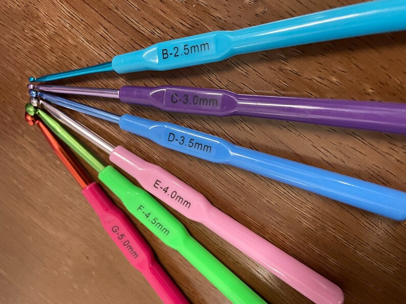 Pu&ograve; includere: Un set di sei ferri da uncinetto di diversi colori e dimensioni. I ferri sono etichettati con la loro dimensione in millimetri: B-2,5 mm, C-3,0 mm, D-3,5 mm, E-4,0 mm, F-4,5 mm e G-5,0 mm.