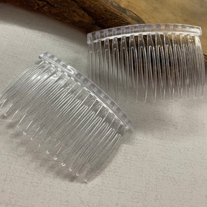 May include: Two clear plastic hair combs with a curved shape and fine teeth.