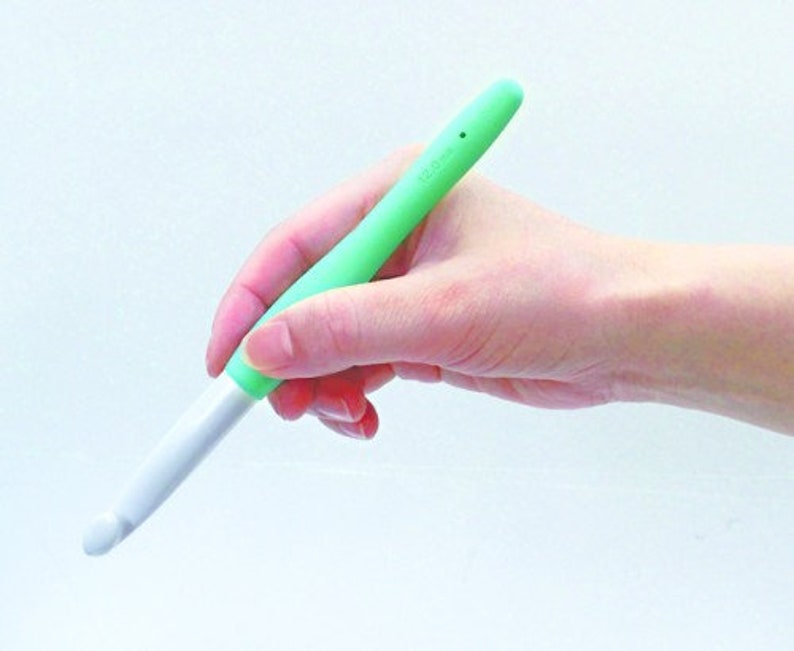May include: A green and white crochet hook with a soft, rubberised grip.