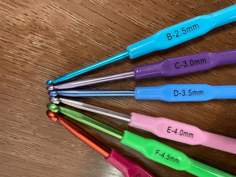 Pu&ograve; includere: Un set di sei ferri da uncinetto in vari colori, tra cui blu, viola, azzurro, verde, rosa e rosso. I ferri sono etichettati con le loro dimensioni in millimetri: B-2,5 mm, C-3,0 mm, D-3,5 mm, E-4,0 mm, F-4,5 mm.