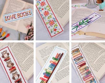 Può includere: Un set di 10 segnalibri a punto croce colorati con vari disegni, tra cui fiori, gufi, libri e un rametto di lavanda. Tutti i segnalibri sono bianchi con un bordo sfrangiato.