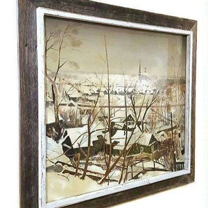 Pu&ograve; includere: Un dipinto di paesaggio invernale incorniciato con una cornice bianca e una cornice esterna in legno marrone. Il dipinto raffigura un villaggio innevato con case e alberi.