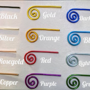 May include: A collection of twelve spiral-shaped wire clips arranged in a grid. Each clip is a different color with its corresponding name printed next to it: Black, Gold, Dark blue, Silver, Orange, Blue, Rosegold, Red, Light blue, Copper, Purple, and Green.