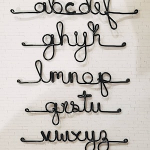 May include: A set of black wire letters forming the lowercase alphabet arranged in five horizontal rows. Each letter is connected by a continuous line, creating a cursive script style. The text Wirecreationsbyjules is visible at the bottom.