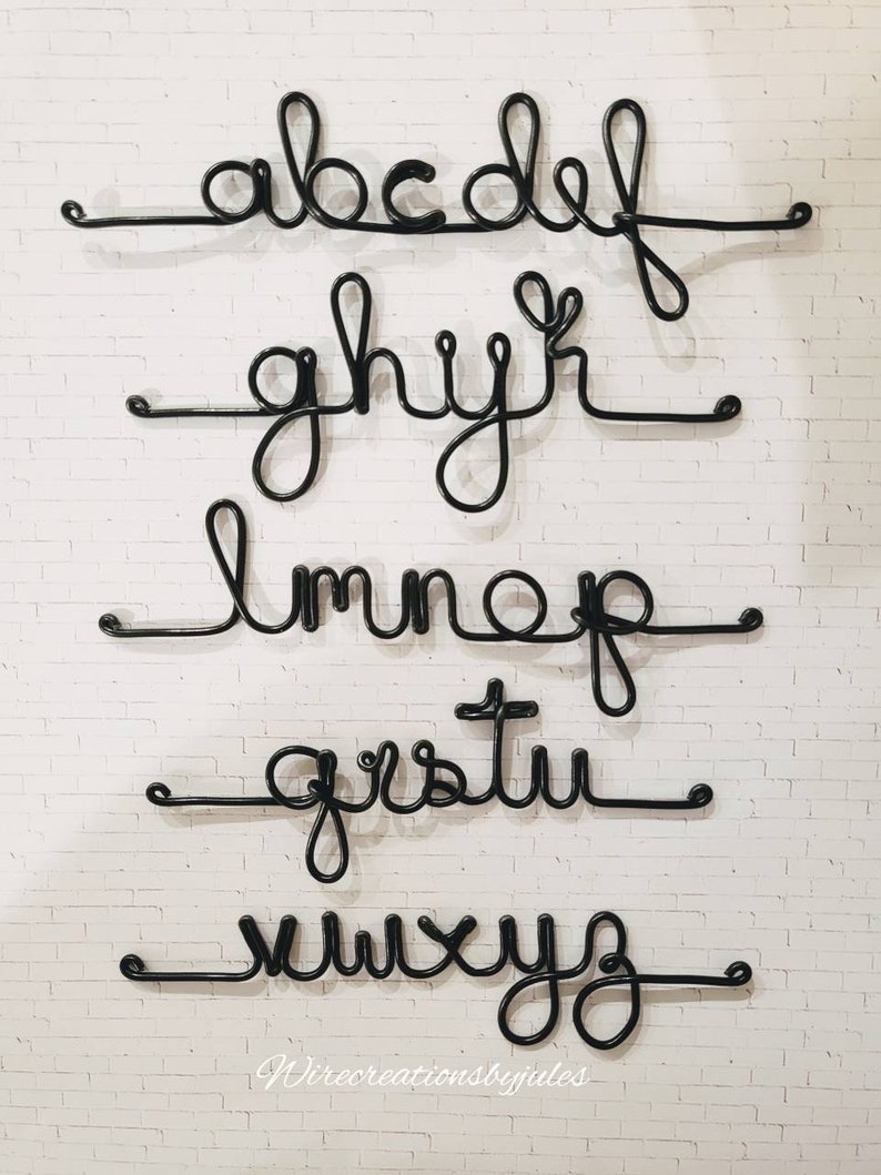 May include: A set of black wire letters forming the lowercase alphabet arranged in five horizontal rows. Each letter is connected by a continuous line, creating a cursive script style. The text Wirecreationsbyjules is visible at the bottom.